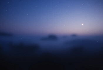 Fototapeta premium A blurry image of a starry night sky with a large star in the middle. The sky is dark and the stars are scattered throughout