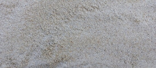Close-Up Texture of Natural Beach Sand.High-resolution close-up image of natural beach sand texture. Fine grains with a mix of light beige and grey tones, ideal for use as background, texture overlays