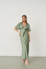 Elegant woman in stylish green dress poses gracefully in a modern studio setting