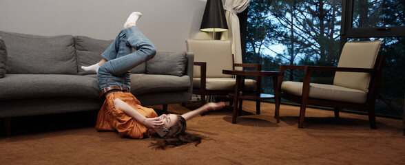 A young woman enjoying playfully lying on the floor in a cozy living room, displaying happiness in...