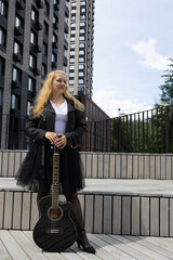 a woman with a guitar in a leather jacket and tutu skirt. A woman plays the guitar