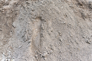 A large pile of dry, granular soil with visible small stones and clumps. Ideal for construction or landscaping projects.