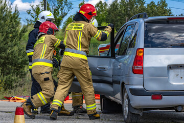 Three firefighters cut open a car after a crash during a rescue operation to pull the driver