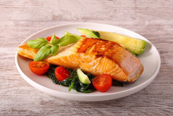 Salmon with spinach and tomato on plate