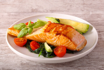 Salmon with spinach and tomato on plate