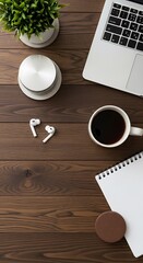 Workspace arrangement featuring laptop coffee earbuds notepad and plant on wooden surface