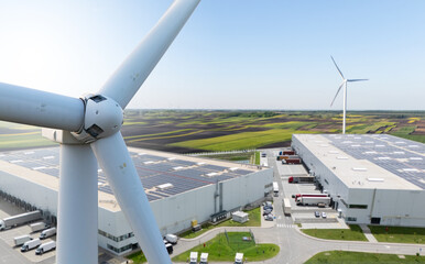 Wind turbine on a background of logistics centers with solar panels on roofs