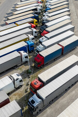 Aerial view of a large truck parking lot at a logistics hub, with multiple commercial semi trucks parked in organized rows