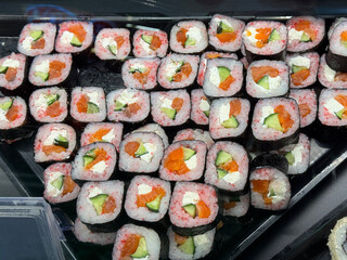 colorful assortment of sushi rolls filled with salmon, cucumber, and cream cheese, wrapped in nori and rice with red tobiko. Perfect for a fresh and delicious Japanese-style meal
