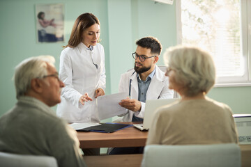 Obraz premium Female nurse and male doctor having an appointment with mature couple in a doctor's office.