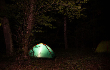Glowing tent at night in the forest.