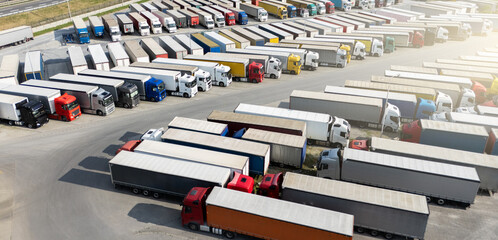 Aerial view of a large truck parking lot at a logistics hub, with multiple commercial semi trucks...