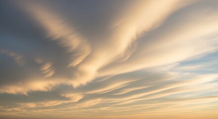 Obraz premium Clouds in a sunset sky display soft, wavy patterns with hues of orange and blue. The scene captures a tranquil atmosphere of nature's beauty.