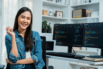 Young Asian in IT developer looking at camera to present with online information on pc with coding...