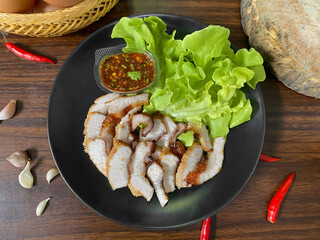 Grilled Pork Neck with Spicy Thai Dipping Sauce and Fresh Lettuce &ndash; Traditional Thai Food on Black Plate