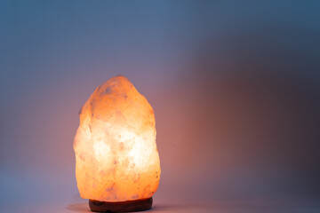 Himalayan salt lamp on blue background.