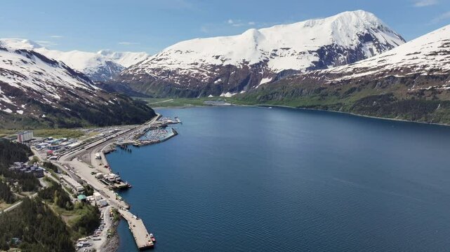 descending above "Passage Canal" with beautiful Alaskan snow covered mountain landscape,  City of Whittier with Port and Harbour and "Anton Anderson Memorial Tunnel" in Background, 4k aerial footage 