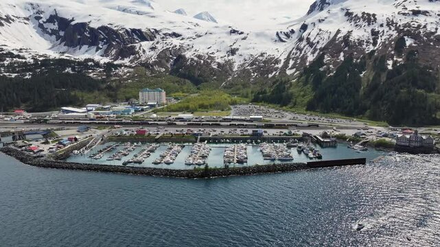 4k aerial video footage - sidewards flying along Alaska mountain Landscape in front of Whittier harbor and port area with Cityscape of Whittier and snow covered mountains in background. 