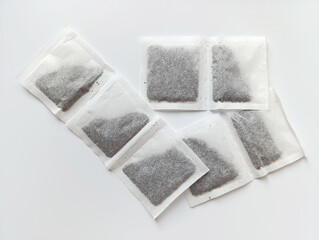 Loose tea bags arranged on a white surface with a minimalist setting, ideal for brewing a warm drink or tea preparation