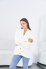 Stylish woman in cozy sweater and boots poses gracefully in modern interior setting