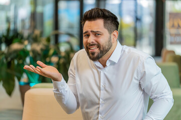 What. Why. Angry Caucasian businessman raising hands in indignant expression, asking reason of...