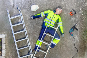 Top view of a construction worker lying unconcious after a workplace accident. Ppe for Safety at...