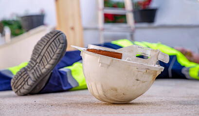 Construction worker lying unconcious after a workplace accident. Ppe for Safety at work.