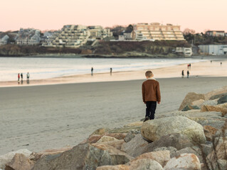 sad boy walking on big rocks at beach