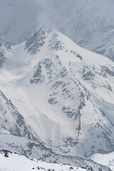 Obraz premium Snow-covered mountain peaks of Mount Elbrus, Kabardino-Balkaria, Russia, captured under dramatic cloudy skies