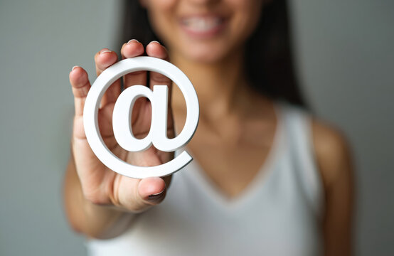 Woman holds at symbol, email sign. Digital communication, online business concept, internet, social media connection. Represents online messaging, virtual interaction, web, apps, social networking.
