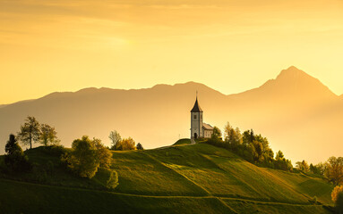 St Primoz Jamnik church overlooking hills during golden hour