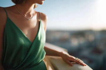 Elegant woman in green dress gazes at city view. Jewelry detail. Ideal for fashion, lifestyle, and elegance themes. Evokes sophistication  aspiration.