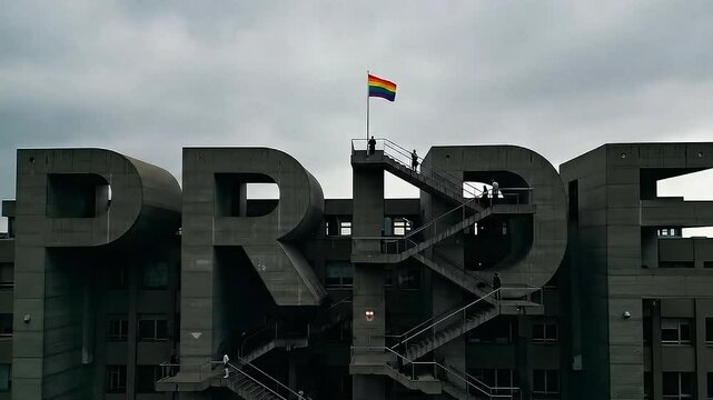 Slow aerial pan of a Brutalist concrete building shaped like the word PRIDE. Moody Full HD video footage symbolizing LGBTQIA+ identity, strength, and hope