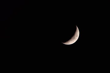 Incomplete new moon close-up on black sky, copy space. Macro photo from telescope