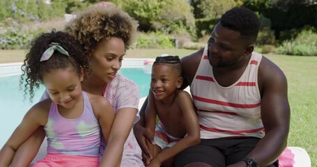 Diverse family tickling son on towel at backyard poolside encouraging first steps, copy space - Powered by Adobe
