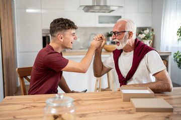 Grandfather and grandson arm wrestling and having fun at home