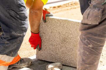 Construction worker positioning granite slab while wearing protective safety gloves at worksite