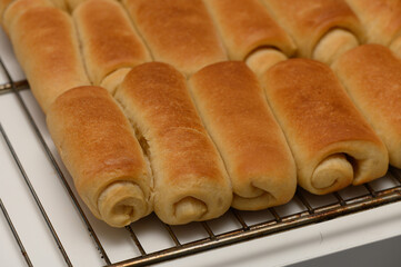 Freshly baked Parker House rolls with golden crust resting on a wire rack to cool.