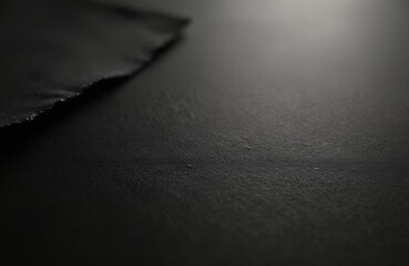 Close-up of torn black paper texture. Abstract grunge background with damage, rough edges. Dark monochrome monochrome image. Modern minimalist design, dark surface, copy space, visual interest.