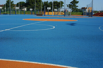 A new modern blue sports ground with a rubberized surface for safe athletic activities, featuring...