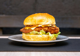 Hamburger with bread, salad, breaded chicken meat, cheese and sausage on top of a table. Delicious fast food burger. Burger ready to eat.
