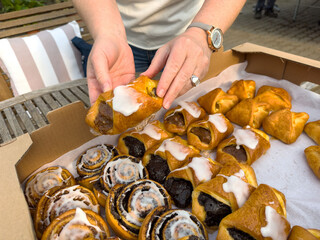 Female hands selecting freshly baked pastries in box outdoors
