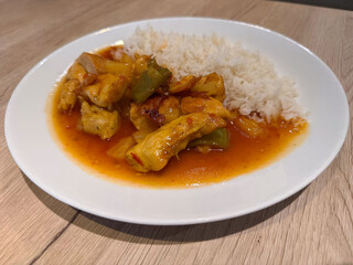 Spicy thai curry chicken with jasmine rice on white plate