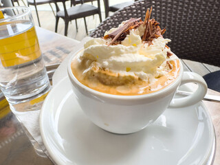Creamy affogato with whipped cream and chocolate shavings on outdoor cafe table