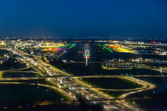 Night aerial view of illuminated airport runway and city lights