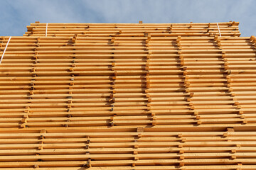 A collection of wooden planks is carefully stacked at a construction site, showcasing their texture...