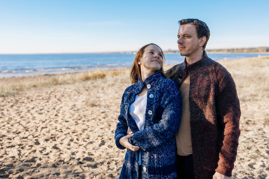 Loving couple walks on beach along sea on sunny autumn day. Weekend and lifestyle concept. High quality photo