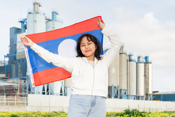 Cheerful asian girl with laotian flag standing in front of factory