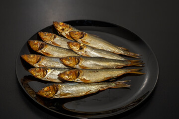 Tasty and salty smoked sprats marinated with salt and spices. Smoked fish marinated with herbs and salt. Smoked fish herring.