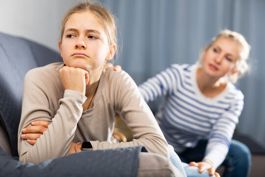 Upset teenager girl after quarrel with her mother in domestic interior, mother consoles daughter - Powered by Adobe